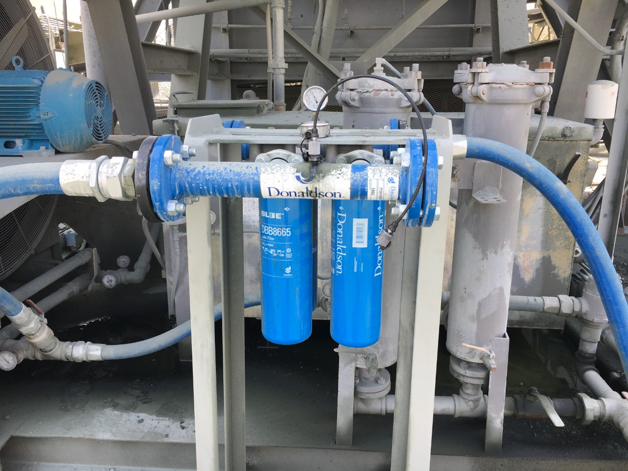Donaldson solution shown in the front with a Mini Mess Sample Port attached to allow proper ISO code readings. The original filters in the back are disconnected, and fluid flows through the Donaldson filters.