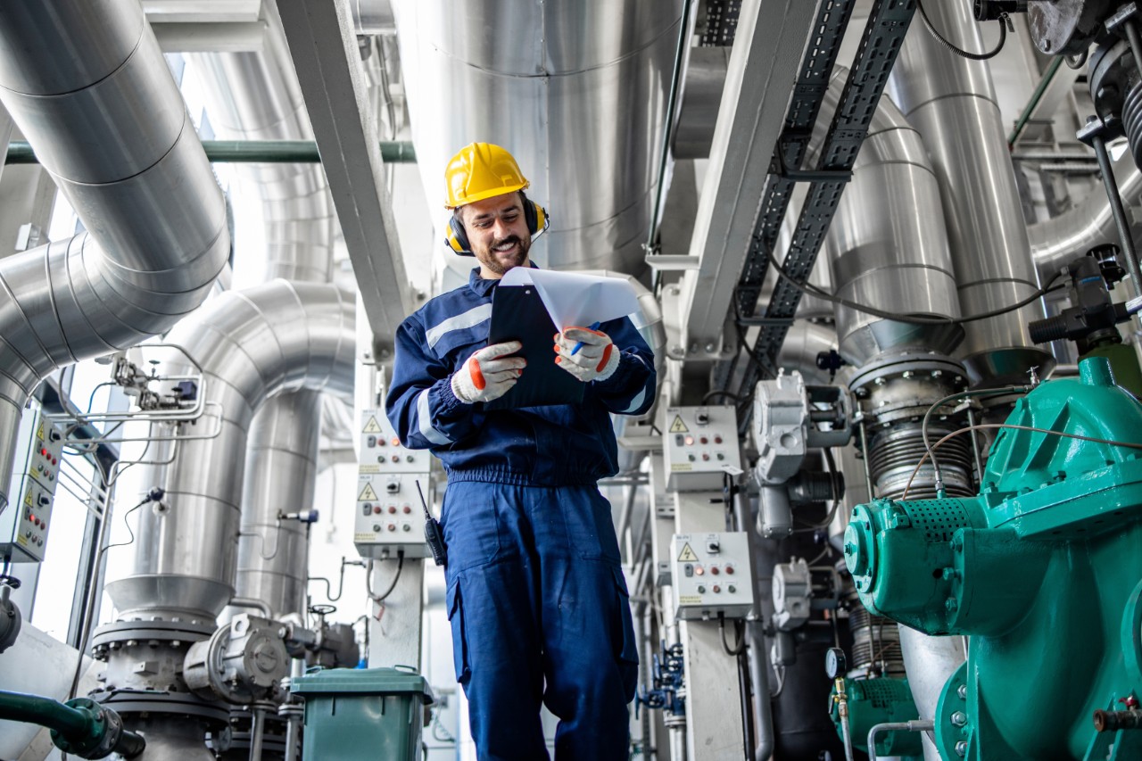 Heating plant supervisor walking through boiler pipeline controlling temperature and gas consumption.; Shutterstock ID 2195345475; purchase_order: IS Power Gen; job: Power Gen Retrofit Brochure; client: Tamara Sissom; other: 