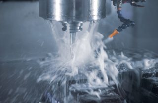 High precision CNC milling machine cutting workpiece with coolant. Industrial metalworking manufacturing